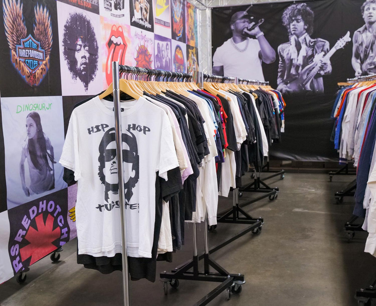 Rails of vintage graphic T-shirts on wooden hangers in the ORA Industries showroom